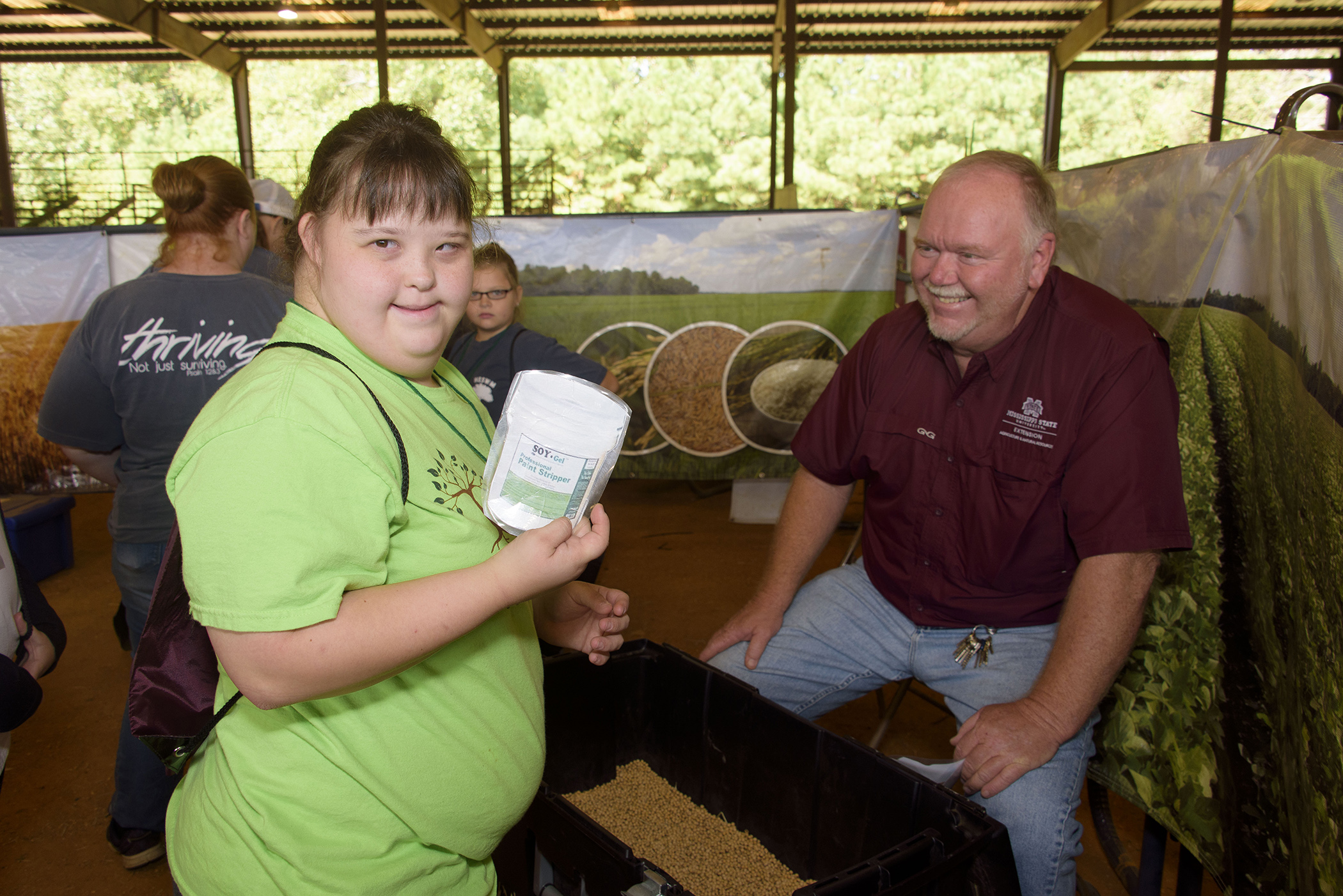 Elementary-age Caucasian girl holds a plastic jar of soy-based paint stripper at a FARMtastic booth.