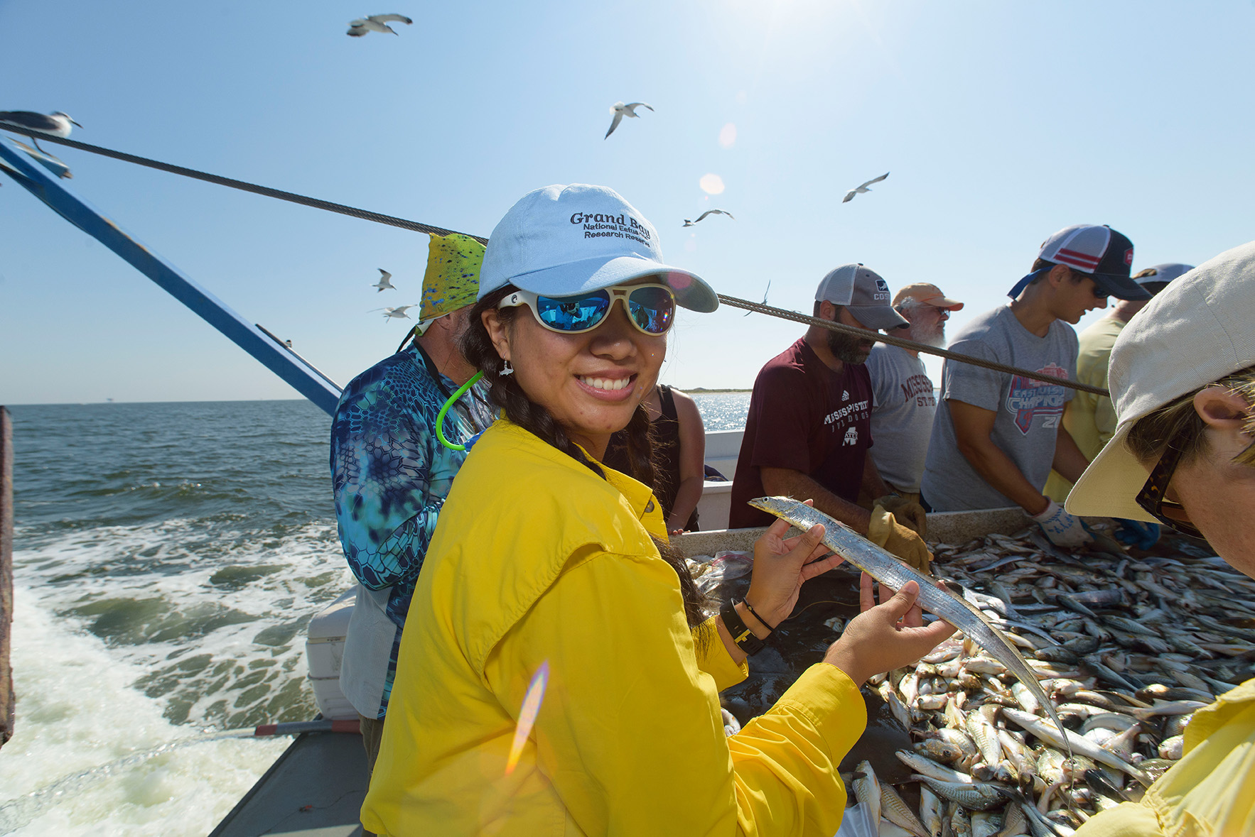 A woman holds a fish after trawling aboard a boat.  