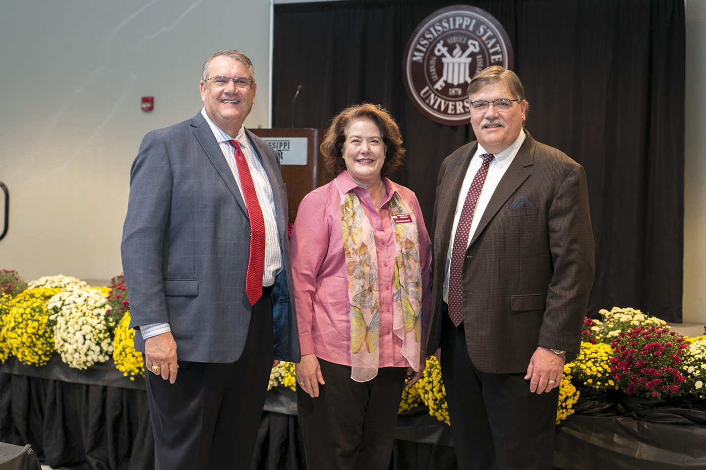 Three Extension administrators stand in an auditorium.