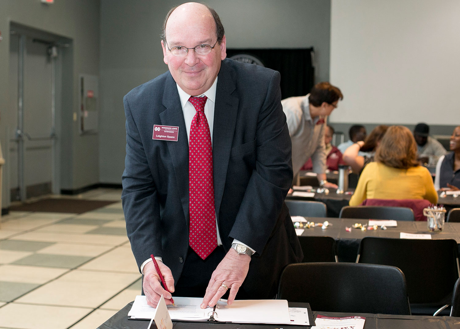 A man in a suit and tie reviews notes in a 3-ring binder.