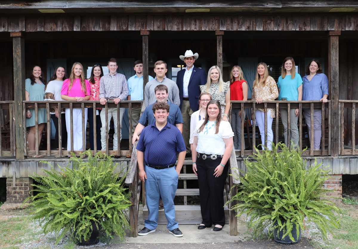 A group of 17 young men and women stand on a porch for a group photo.