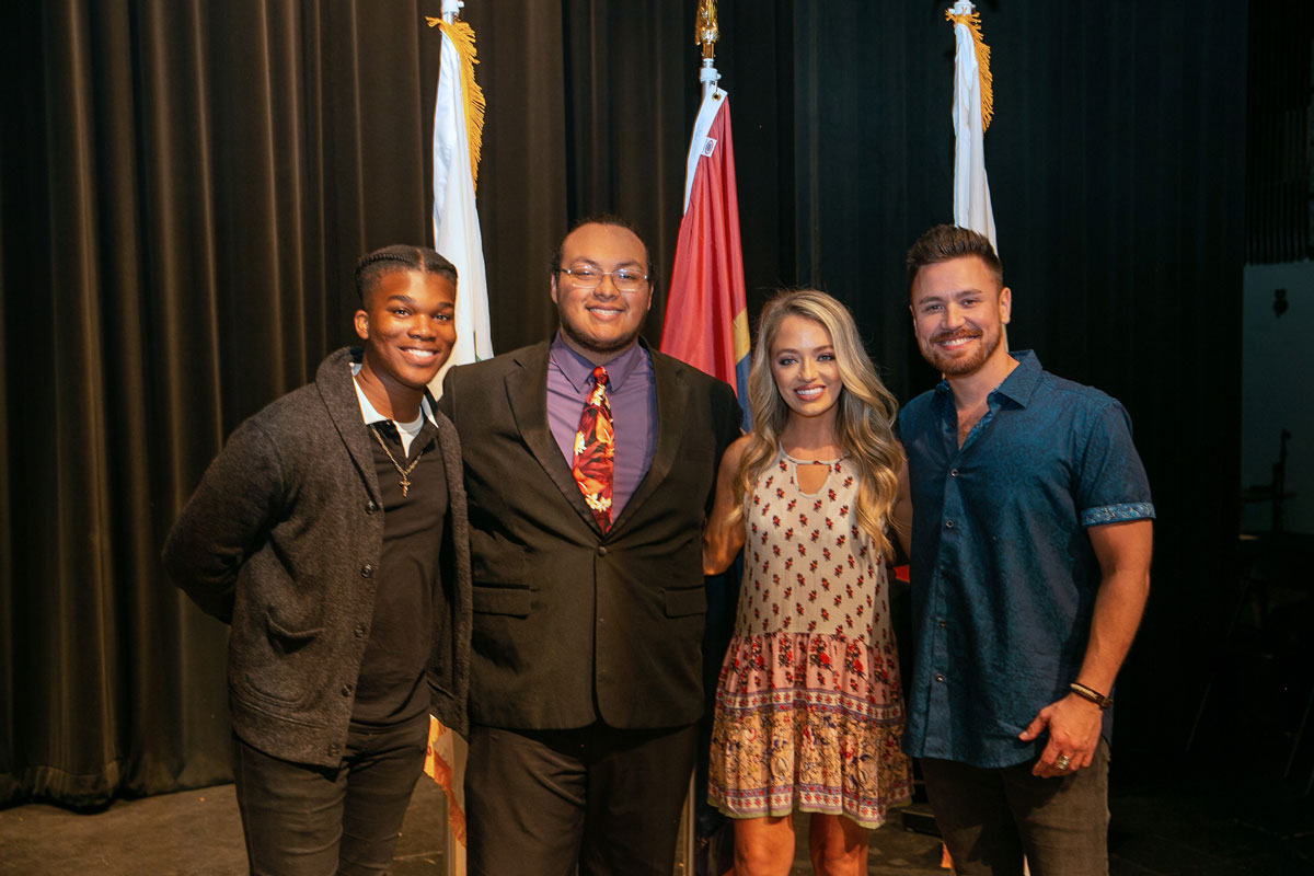 A group photo of three young men and one young woman.