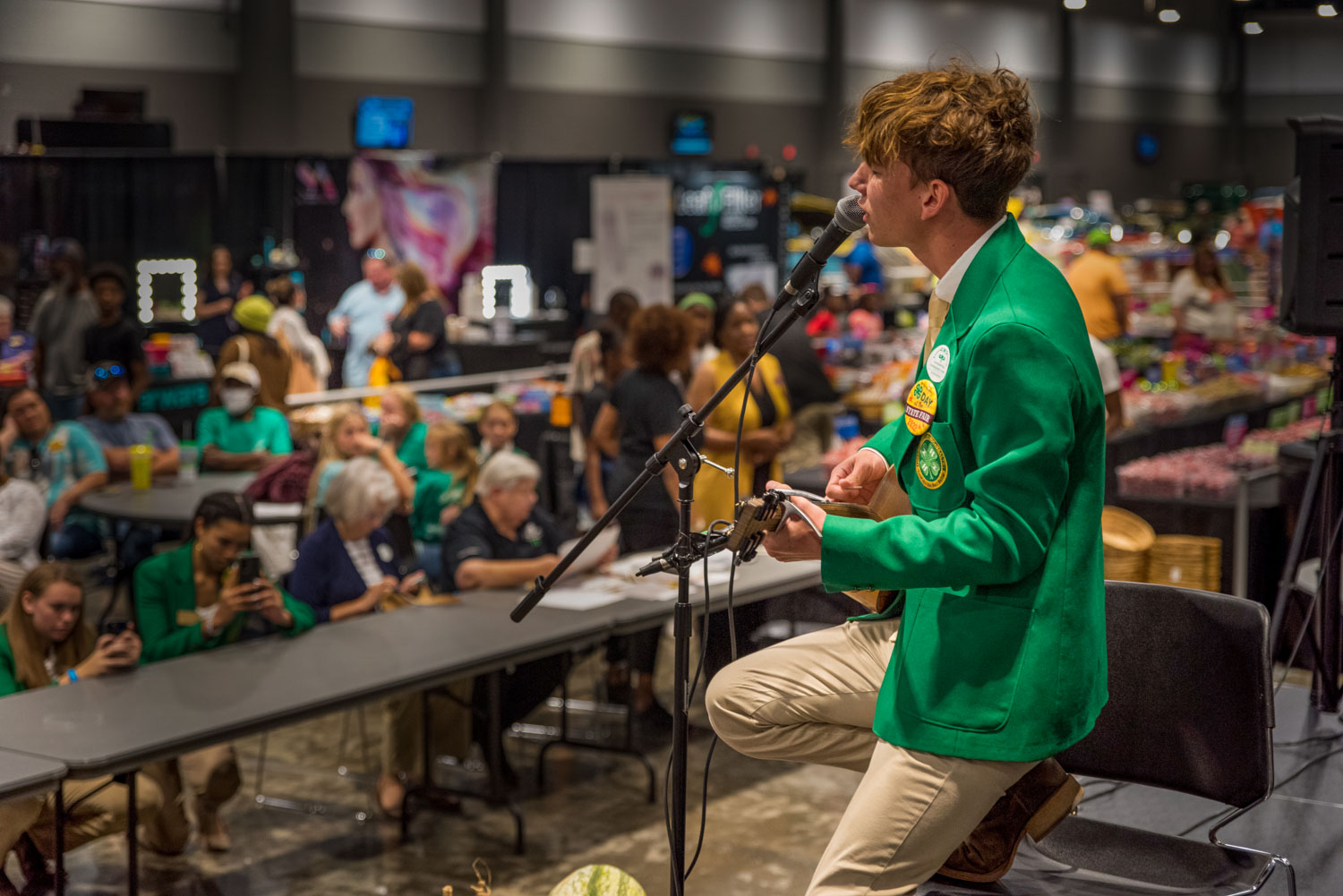 A teenage boy singing into a microphone and playing guitar.