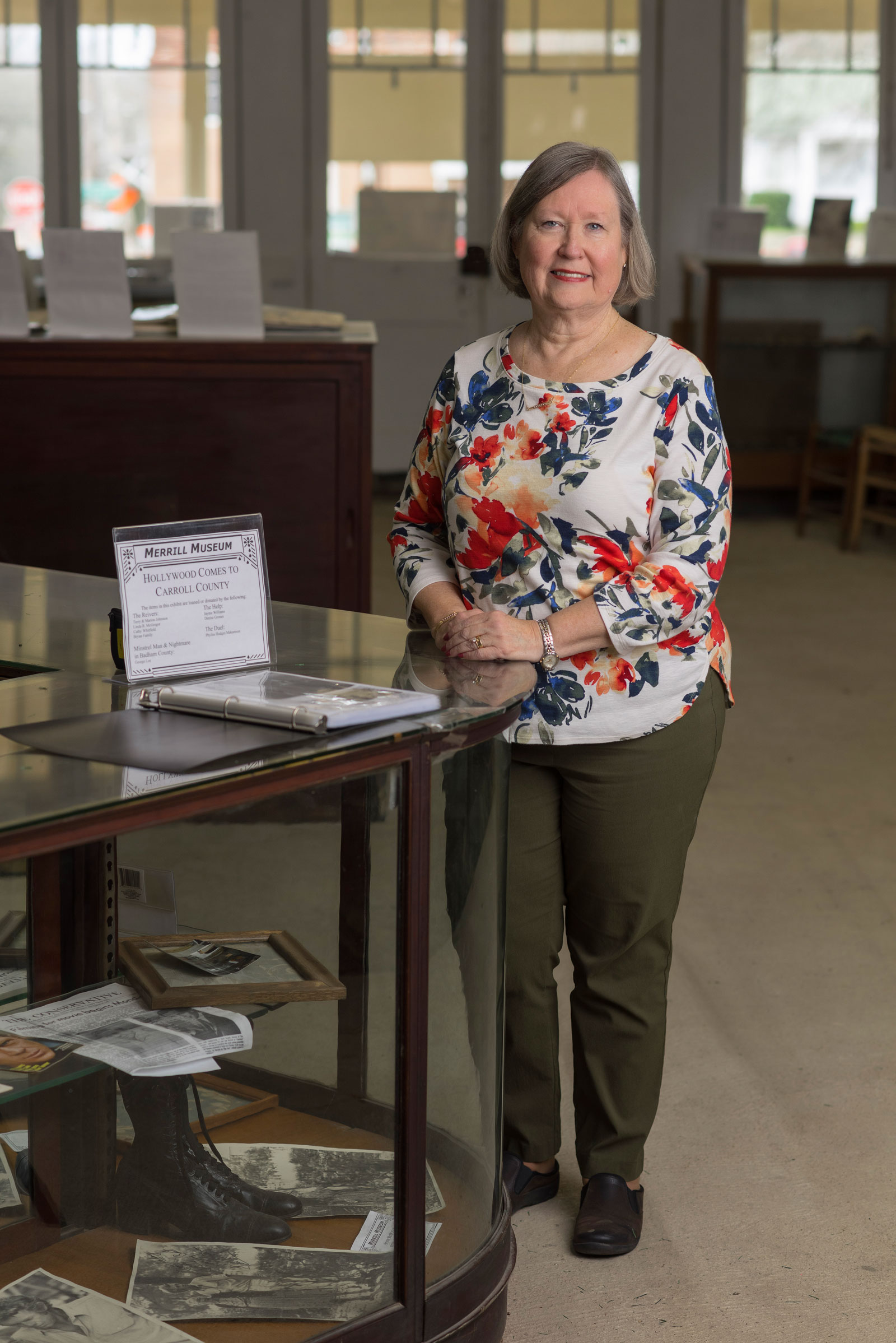 A smiling woman stands beside a museum display.