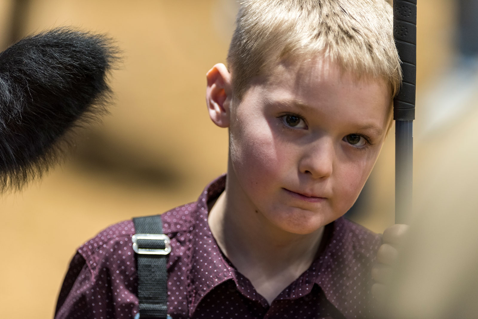 A boy leaning on a thin black column.