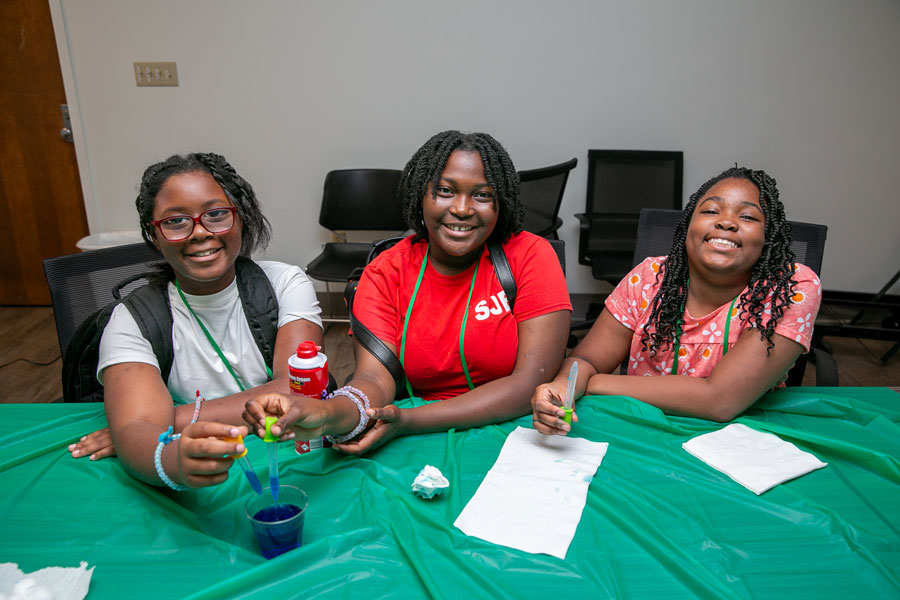 Three girls, smiling and holding droppers.