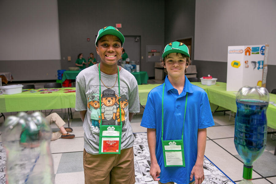 Two boys, wearing green hats and smiling.