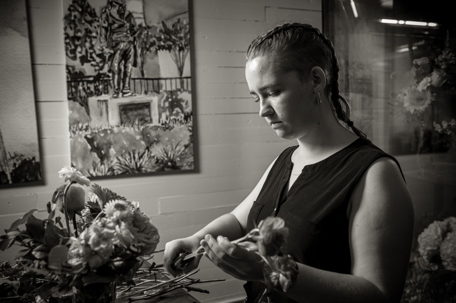 A black-and-white image of a young woman arranging flowers.