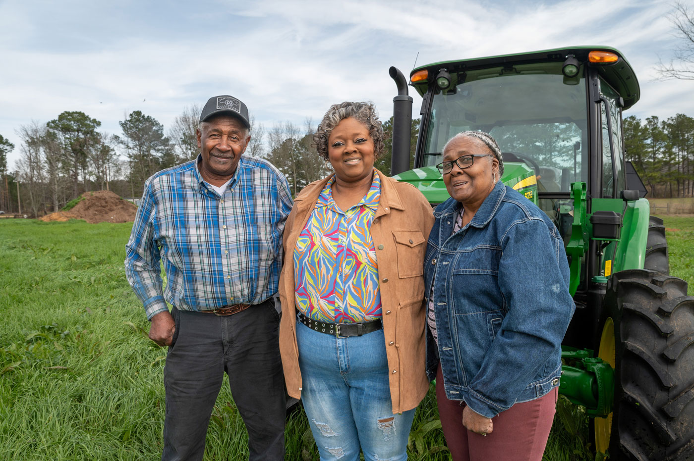 A man and two women standing in front of a tractor.