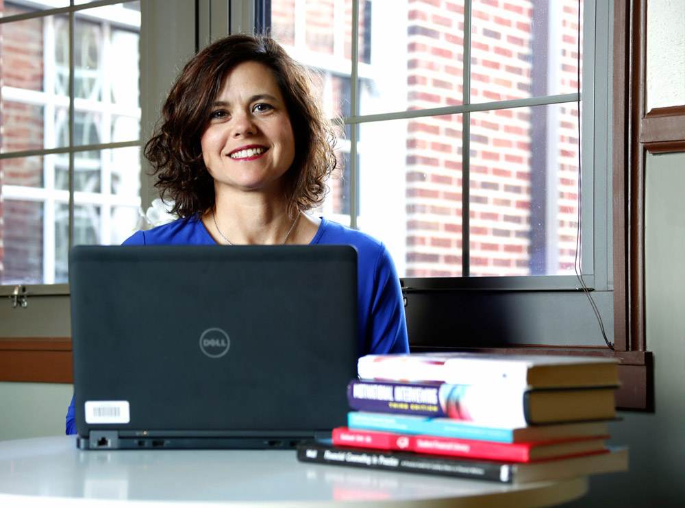 •	Lady sitting at desk with laptop and books