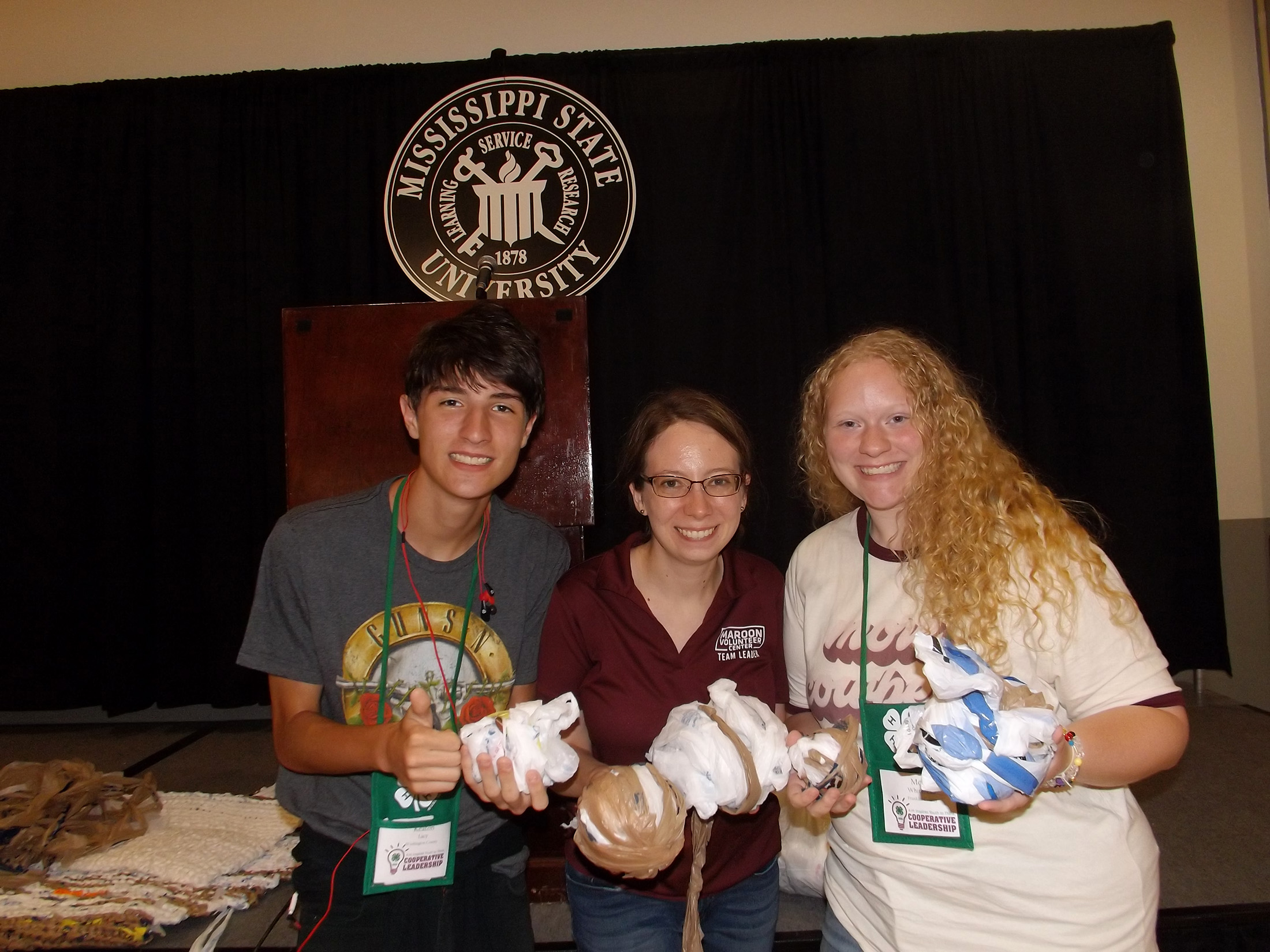 Two young women and a young man pose with plarning material for mattresses.