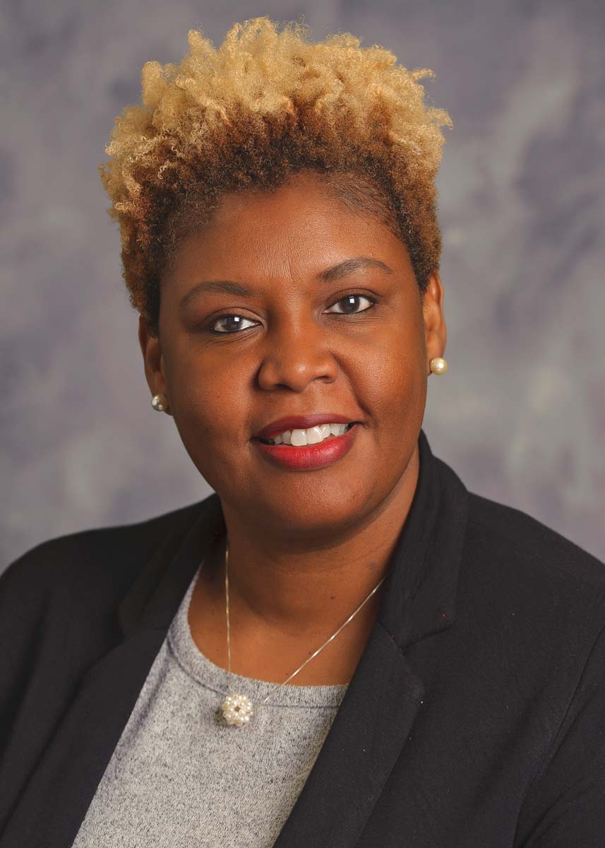 A headshot of a Black, blond woman, smiling.