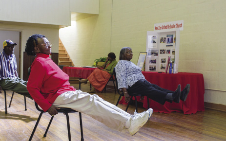 elderly ladies using chairs to exercise