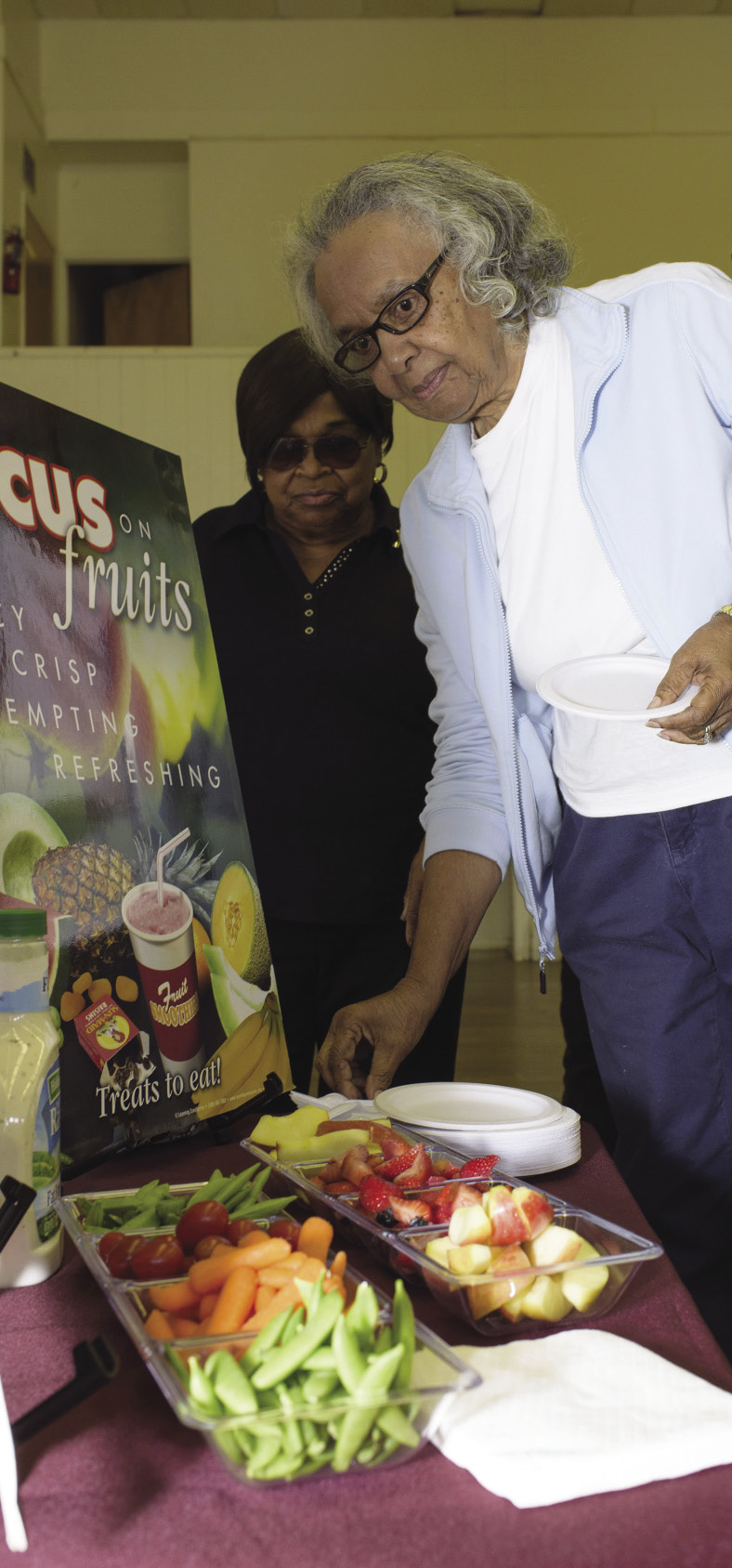 elderly women prepare to serve their plates from a variety of healthy fruits and vegetables.