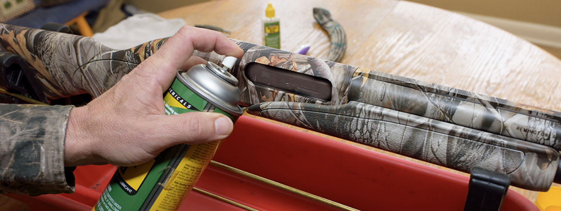 A person uses a can of compressed air to clean debris from an ammunition chamber.