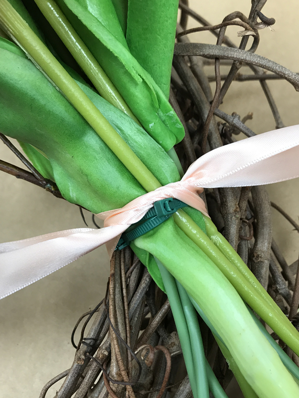 Pink ribbon wrapped around zip-tied flower stems.