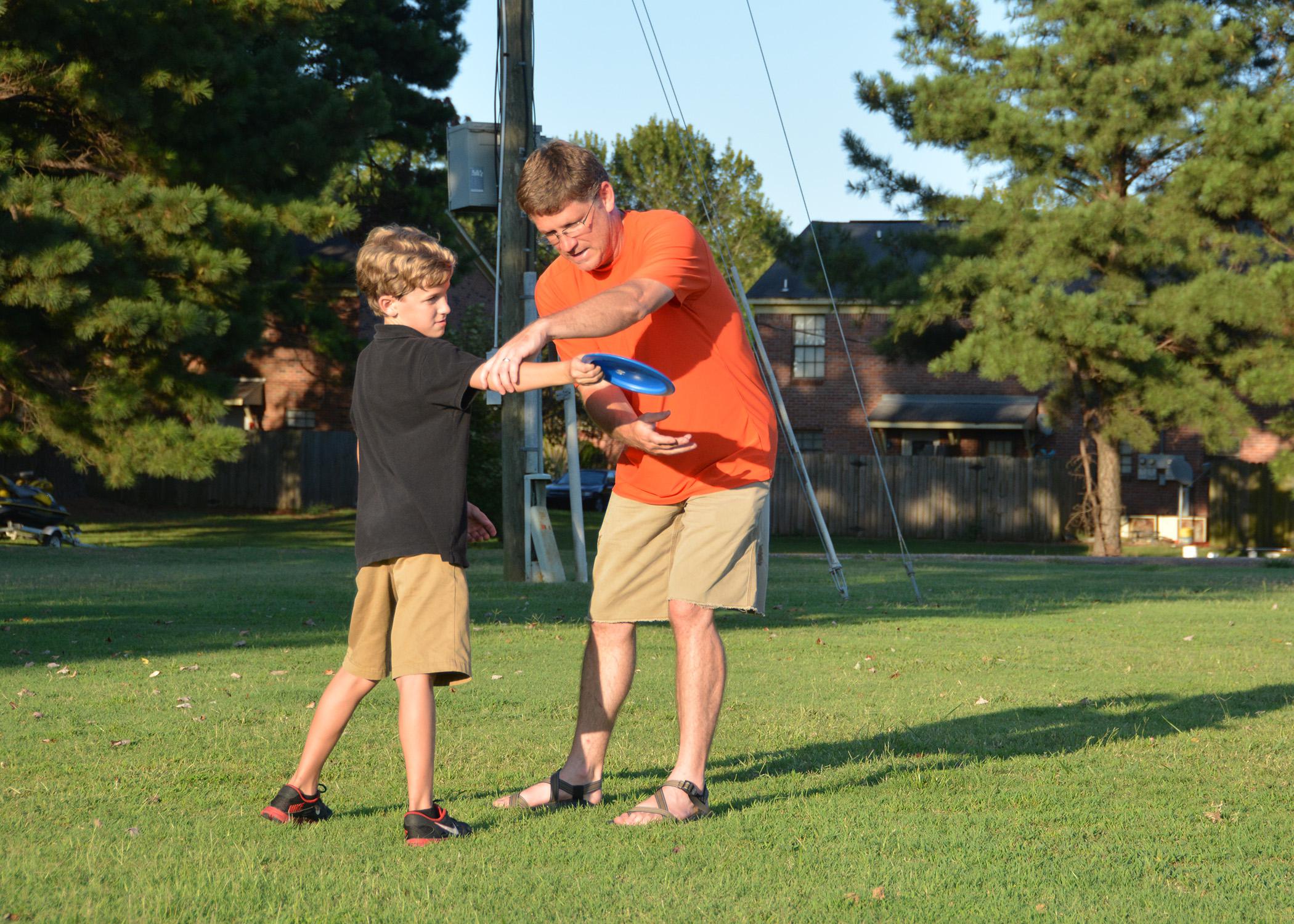 Eddie McReynolds of Starkville helps his 10-year-old son, Reece, develop his throwing skills for a game of disc golf. The McReynoldses practiced together near the Starkville Sportsplex on Sept. 3, 2014. (Photo by MSU Ag Communications/Linda Breazeale)