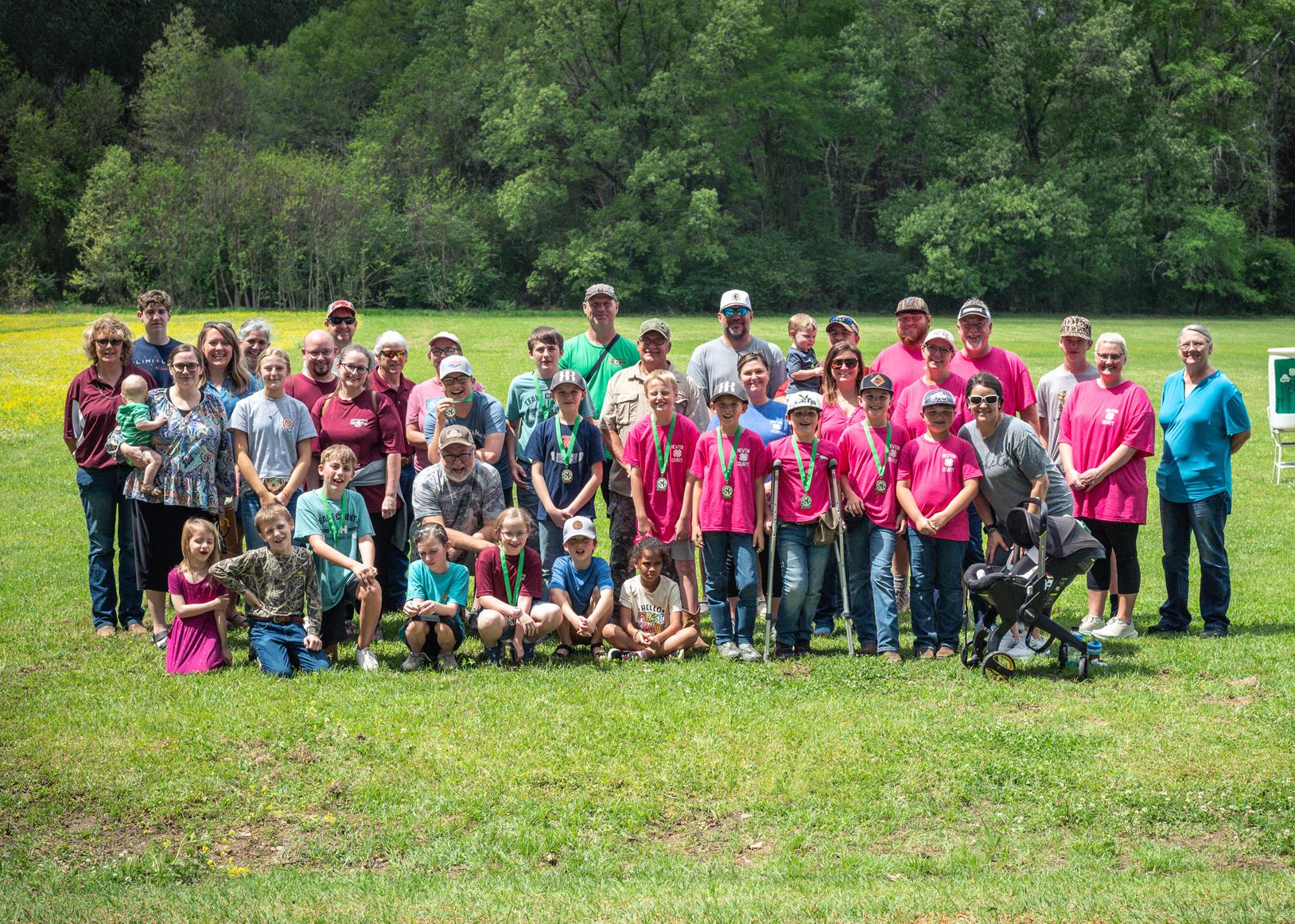 A large group of adults and children gathered on a grassy plain.