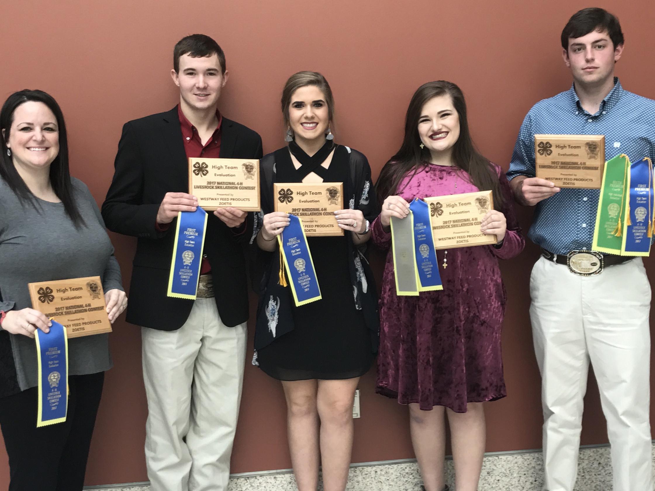 Five people stand in a row holding their awards. 