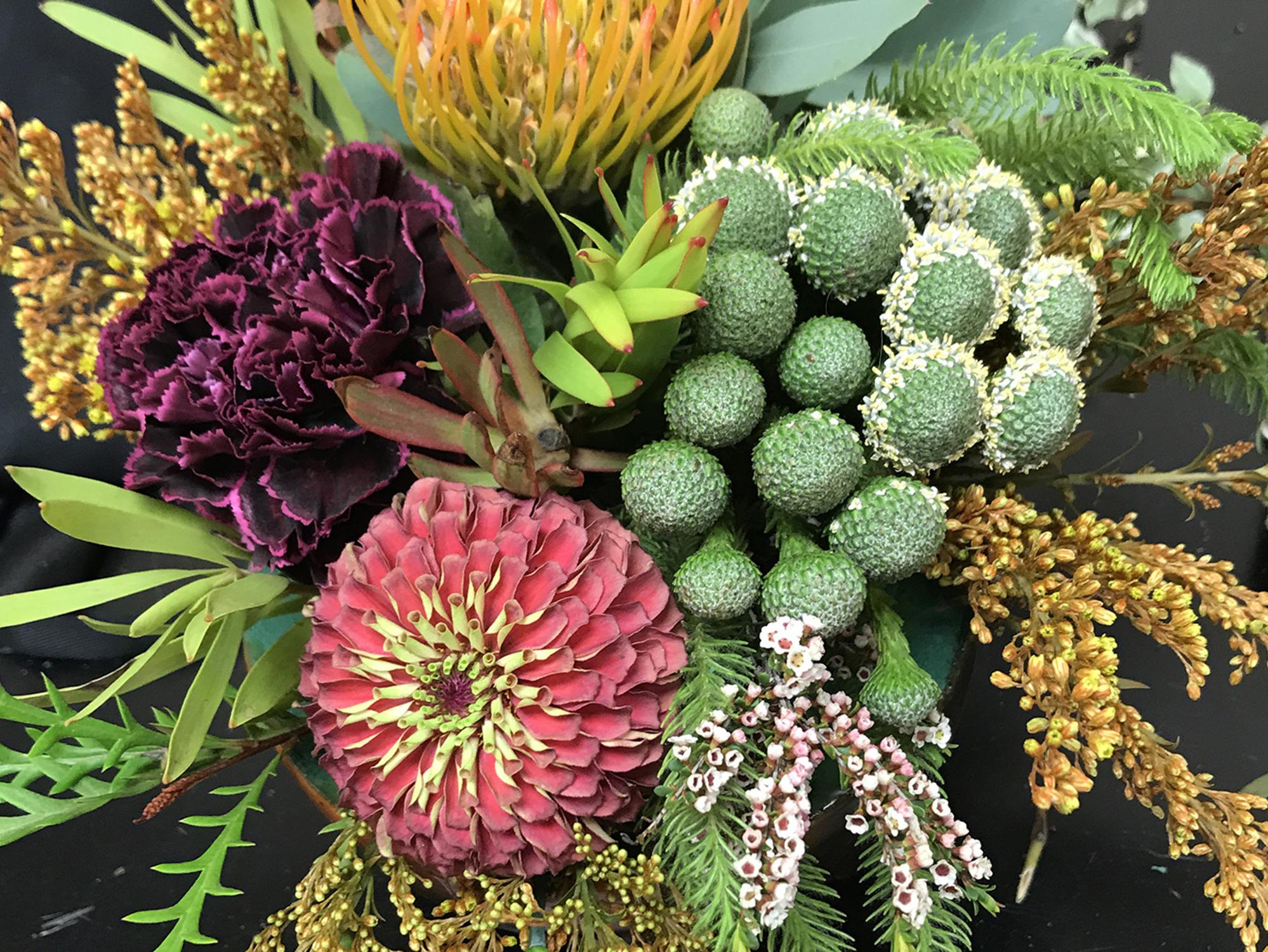 A flower arrangement with various types of flowers and greenery is displayed.