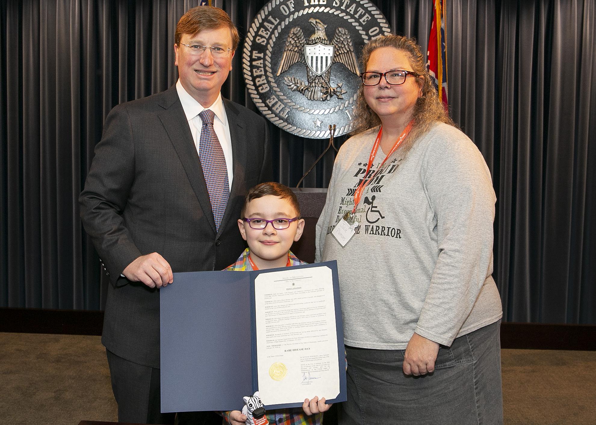 Three individuals pose with a newly signed proclamation.