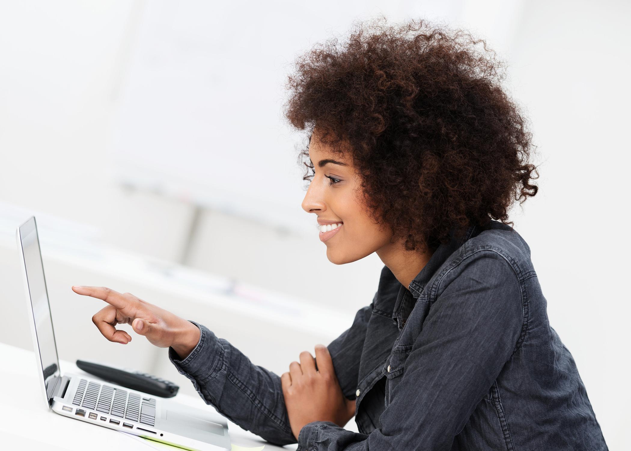 Woman points at computer screen.