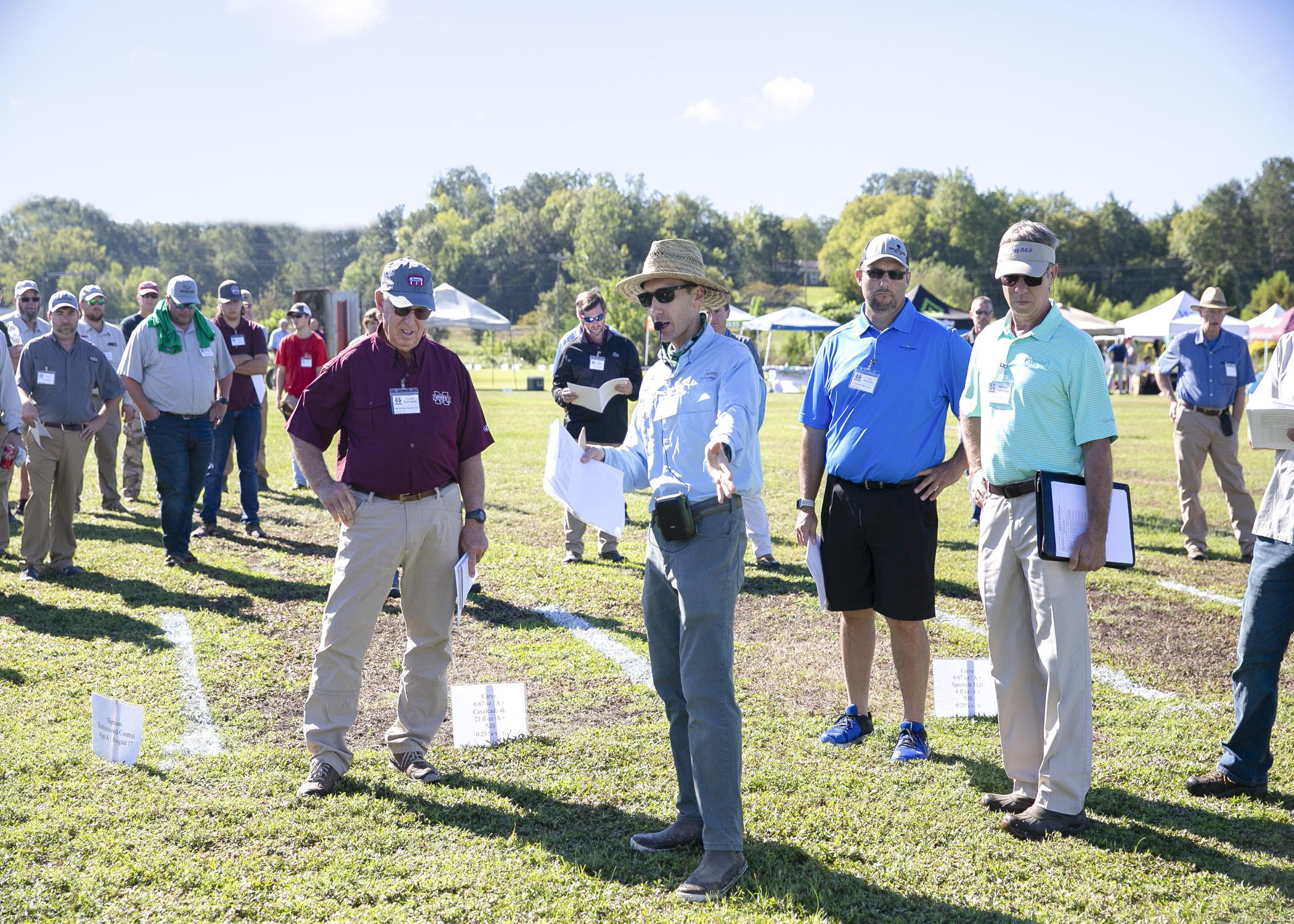 A group of people stand in a grassy field.