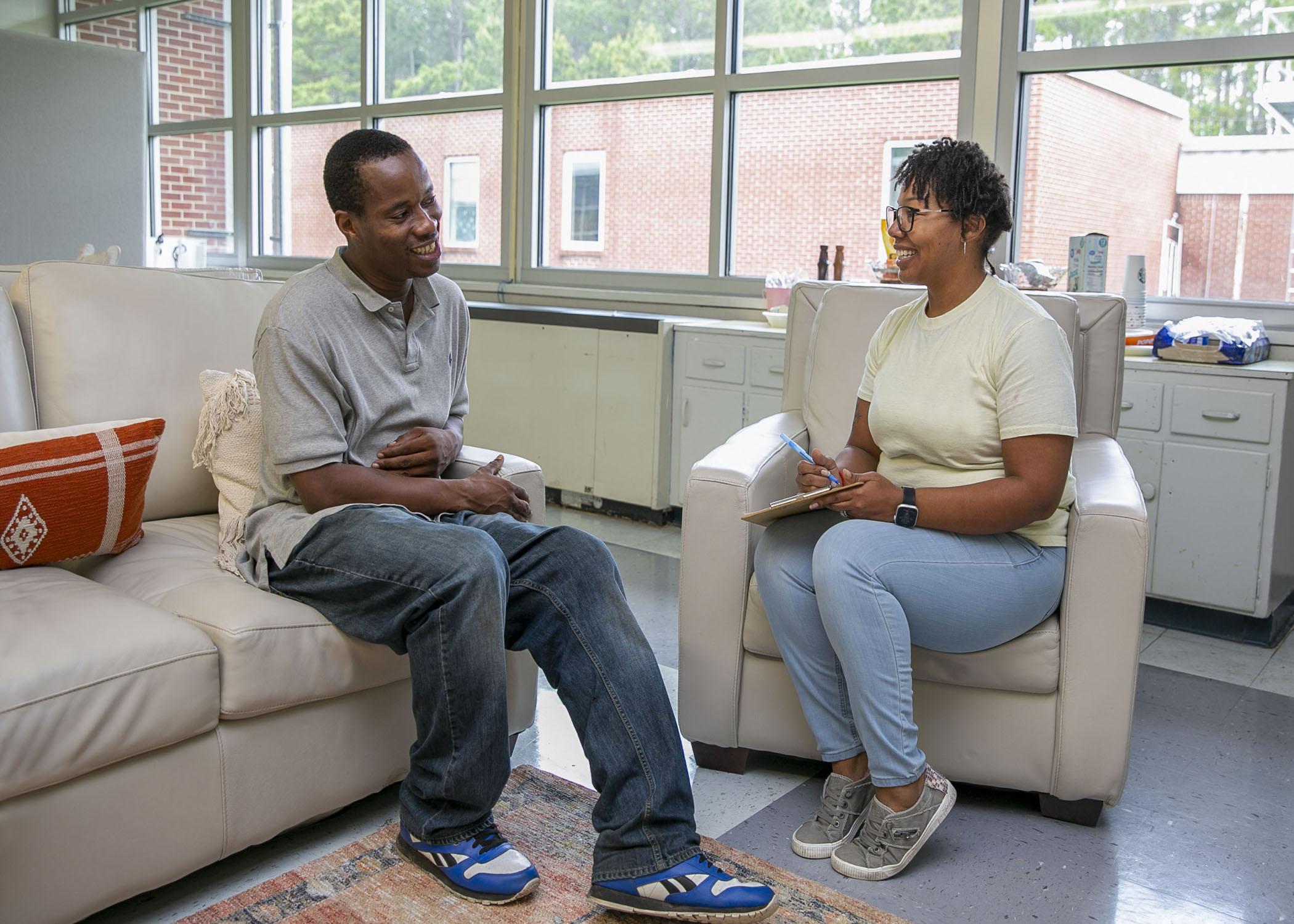 A man and woman sit opposite one another while talking.