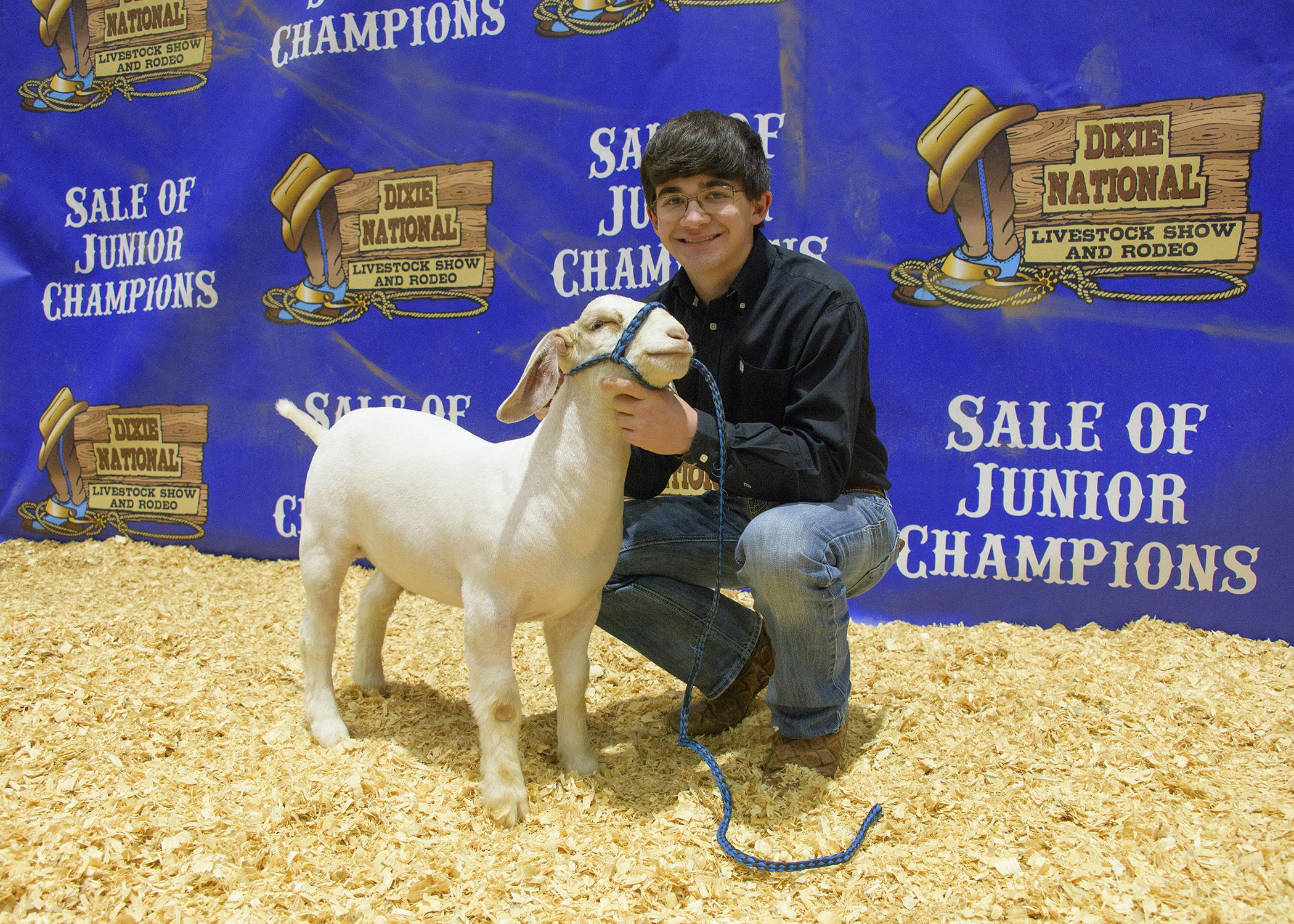 A teenage boy poses with a goat.