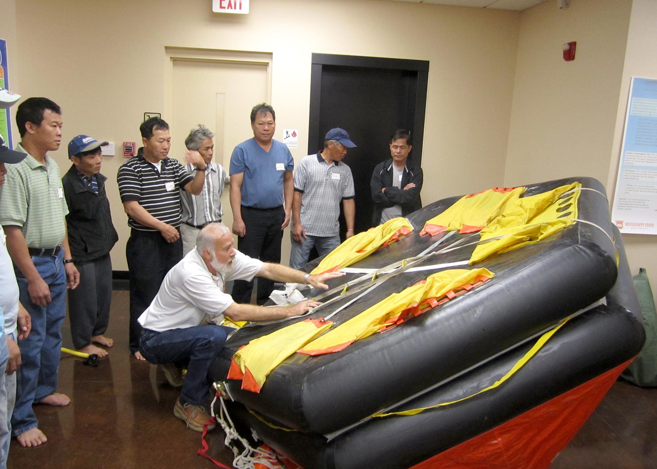 Dave Burrage, Mississippi State University Extension Service professor, demonstrates safety features on a life raft used aboard commercial fishing vessels. (Photo by MS-AL Sea Grant Consortium/Melissa Schneider)