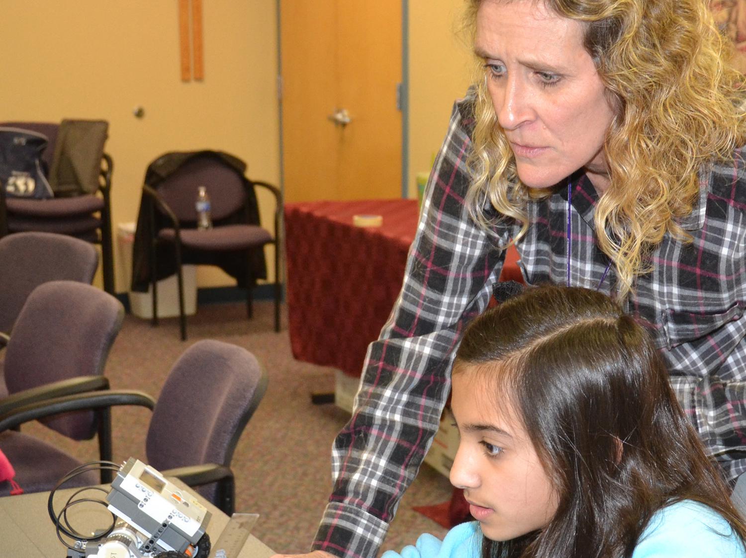 Khadeeja Baig enters information into the computer that will program her robot to turn in a circle as children’s librarian Becky Bowen looks on. Baig is one of 15 children enrolled in the second session of a six-week robotics course at the Rebecca Baine Rigby Library in Madison. (Photo by MSU Extension Service/Susan Collins-Smith)