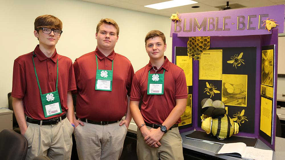 3 young men with bumblebee exhibit.