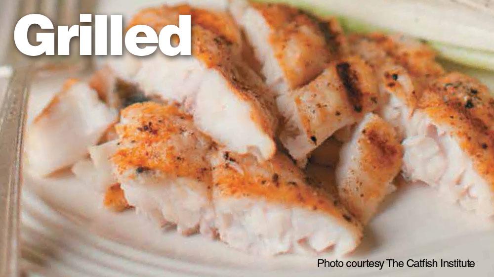 Close-up photo of flaked, grilled catfish served on a white plate 