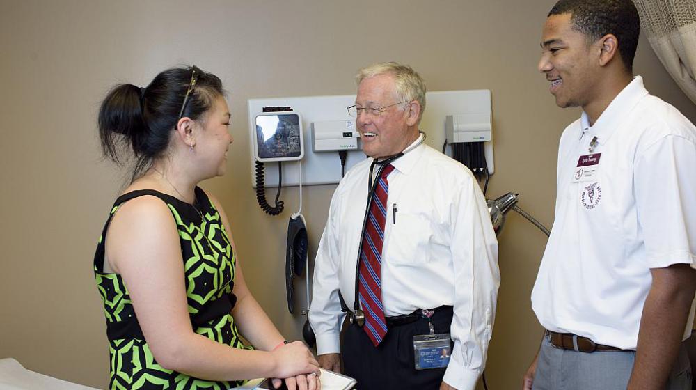 Rural doctor with student shadow seeing patient.