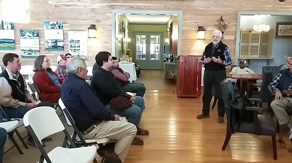 Man giving lecture to a group of seated listeners.