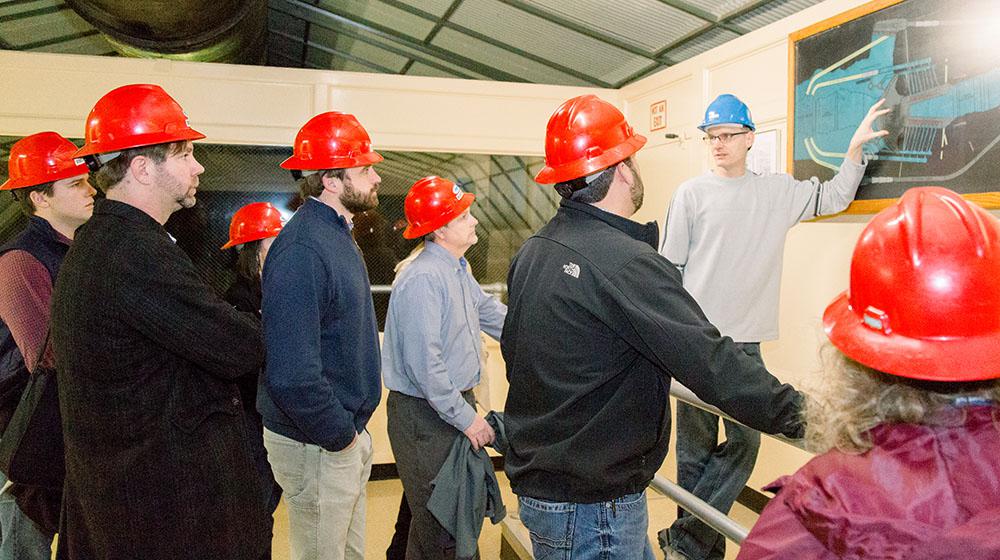 Group in hard hats looking at dam blueprints.