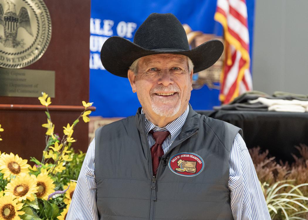 Auctioneer wearing a cowboy hat is smiling.