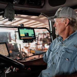 A man driving a tractor and watching digital screens