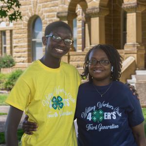 A young man wearing a yellow T-shirt stands with his arm around his mother.