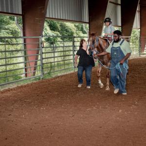 A boy riding a horse, with a man on one side and a woman on the other.