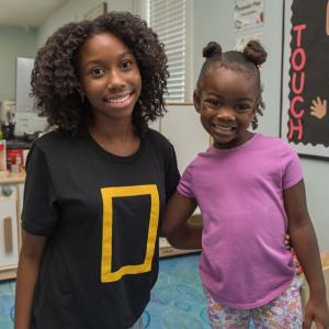 A teen girl and a female toddler smiling at the camera.