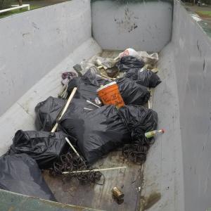 Full black trash bags gathered in a large metal container.