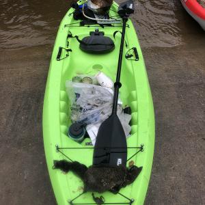 Bright green kayak holding trash at the edge of water. 