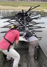 Mississippi State University students Jason Bies, left, and Clint Lloyd install an artificial, commercially-available fish habitat at Blackjack Pond on the MSU campus. (Photo by MSU Extension Service/Wes Neal)