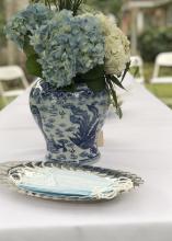 A silver tray holding paper masks sits in front of a vase of flowers on a table.