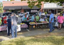 Shoppers browse products set up outdoors on tables.
