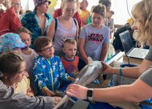 Children feel the skin of a shark held by a marine fisheries biologist.