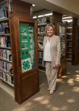 U.S. Senator Cindy Hyde-Smith stands next to a display case in a library.