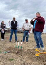 Four people stand outside during an installation demonstration.