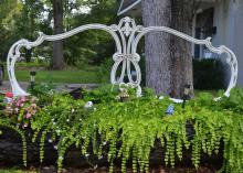 A metal headboard rises above a fairy village set among ferns.